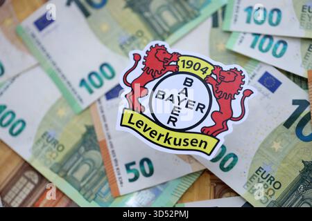 KIEV, UKRAINE - 23 FÉVRIER 2025 Bayer 04 Leverkusen football badge se trouve sur un grand montant de centaines d'EUROS DE billets d'argent Banque D'Images