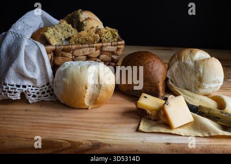 Une variété de pains blancs et complets fraîchement cuits et des morceaux de fromage à pâte dure rustiques pour un repas sain et chaleureux. Banque D'Images
