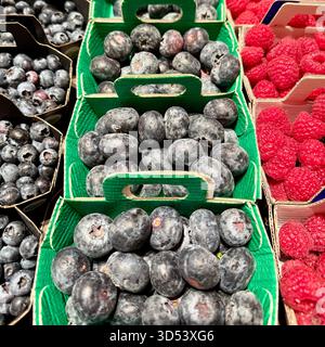 Gros plan plein cadre de cartons de bleuets frais et de framboises à vendre dans un marché Banque D'Images