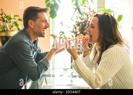 Un couple aimant partage un moment tendre dans la cuisine moderne, en dégustant de la pizza Banque D'Images