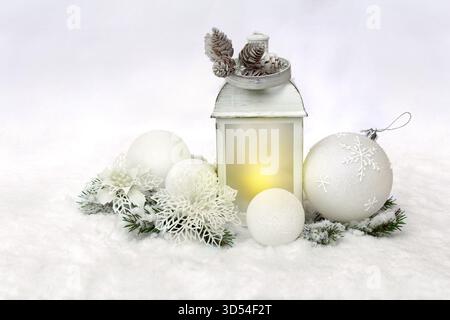 Décoration de Noël. Lanterne de Noël, boules blanches, cônes, fleurs ajourées blanches, brindilles arbre de Noël sur neige, neige couverte sur fond clair Banque D'Images