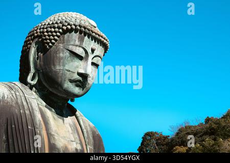 Un gros plan du Grand Bouddha (Daibutsu) au temple Kotoku-in contre un ciel bleu clair Banque D'Images
