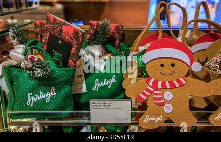 Zurich, Suisse - 24 novembre 2024 : bonhomme en pain d'épices festif et sacs-cadeaux verts remplis de délicieux chocolats, exposés chez Sprungli Chocolatier Banque D'Images
