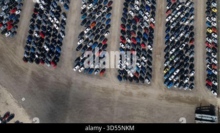 Vue aérienne d'un grand terrain rempli de rangées de voitures garées de différentes couleurs et tailles, étroitement emballées ensemble sur un terrain de terre à Copart yard, York Banque D'Images