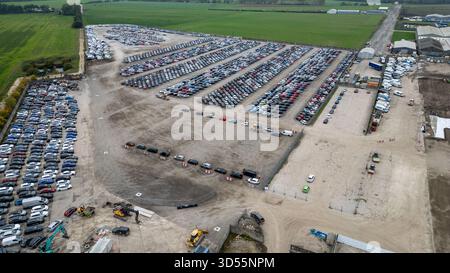 Vue aérienne d'un grand terrain de stockage extérieur rempli de rangées de véhicules, avec les champs verts environnants et les bâtiments industriels à Copart Yo Banque D'Images
