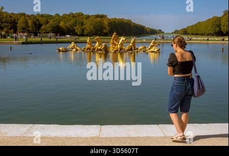 Femme à la Fontaine Apollon dans les jardins du château de Versailles, France Banque D'Images