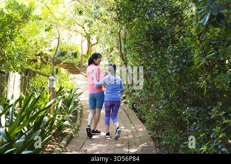Promenez-vous en famille chinoise reliant les bras le long d'un chemin de jardin pavé de briques, avec borne lumineuse Banque D'Images