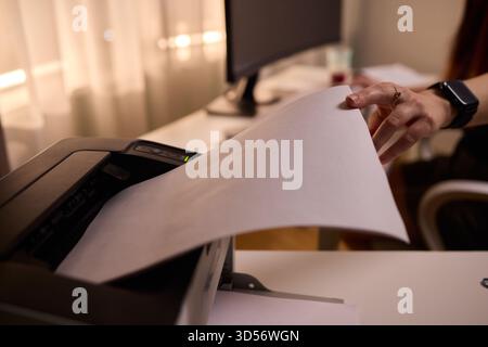Environnement de travail avec chargement du papier, assistant insertion du papier dans le bureau de l'imprimante laser, scène de bureau calme avec assistant insertion du papier dans Banque D'Images