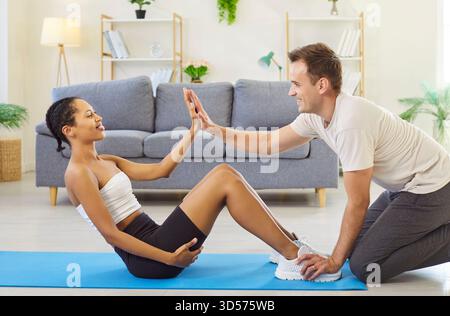 Mari de soutien se tenant les pieds pendant que la femme fait des sit-ups, partageant un high-five Banque D'Images