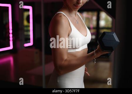 Femme soulevant Dumbbell dans Gym Banque D'Images