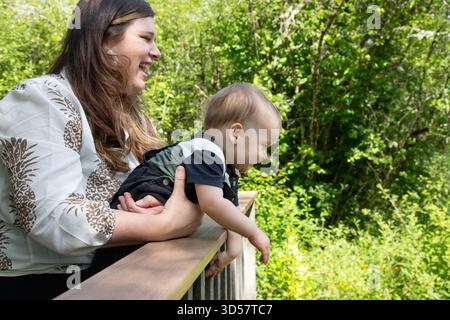 Femme souriante debout sur un pont avec son fils bébé appuyé sur les balustrades Banque D'Images