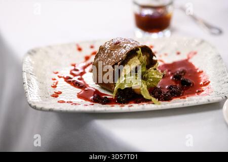 Gros plan d'une tranche de pain suisse au chocolat fourré de crème fouettée et d'une garniture de coulis de fruits Banque D'Images