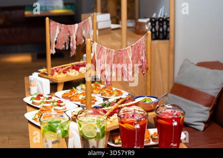 Service exquis original de snacks à la viande, jambon, jambon, salami, assortiment de fromages, olives, sauce. Antipasti sur la table dans un restaurant, italien Banque D'Images
