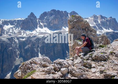 Randonneur assis sur le sommet de la montagne profitant de beaux paysages de montagne - Dolomites Italie. Banque D'Images