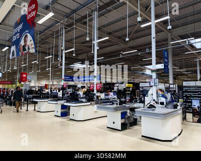 Manchester, Royaume-Uni - 30 septembre 2025 : comptoirs de caisse occupés dans un magasin Manchester Tesco montrant le libre-service et le personnel serviable. Banque D'Images