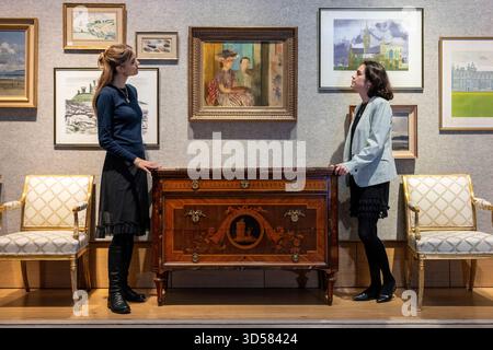 Londres, Royaume-Uni. 14 novembre 2025. Membres du personnel avec une commode Lombard exceptionnelle du début du 19ème siècle de Giuseppe Maggiolini, vers 1805-1810, (estimation £50 000 - £80,000) sous Victor Pasmore R.A. (Britannique, 1908-1998) "The Painting Lesson", 1939, (estimation £30 000 - £50,000) lors d'un aperçu de la vente Lady Glenconner, My Life in Objects à Bonhams. Lady Glenconner était demoiselle d'honneur au couronnement de la reine Elizabeth II en 1953, et Lady in Waiting de son amie d'enfance, la princesse Margaret. Les lots seront mis aux enchères dans les galeries Bonhams New Bond Street le 18 novembre. Crédit : Stephen Chung Banque D'Images