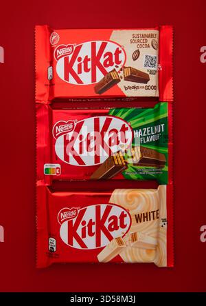 LONDRES, Royaume-Uni - 27 JUIN 2025 : diverses barres de biscuit de gaufrettes de chocolat KitKat sur fond rouge. Banque D'Images