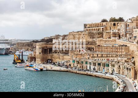 La Valette, Malte - 10 avril 2025 : vue sur le front de mer historique de la Valette et ses fortifications, avec des ferries amarrés et des bateaux de croisière dans le Grand Port Banque D'Images