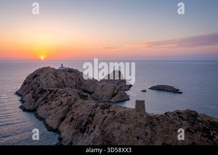 Coucher de soleil sur Rocky Island avec phare et sentier sinueux le long de la côte, Corse, France Banque D'Images