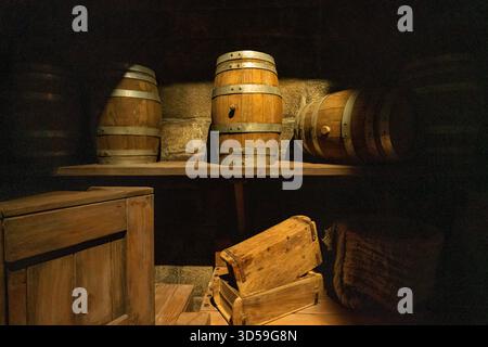 Barils et caisses en bois rustiques exposés dans une cave faiblement éclairée à Abu Dhabi, aux Émirats arabes Unis. L'éclairage chaleureux et les textures vieilles créent un ancien Banque D'Images