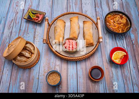 Nature morte minimaliste avec trois rouleaux de printemps parfaitement alignés sur marbre noir, accompagnés de germes de haricots et d'un bol minimaliste de sauce hoisin Banque D'Images