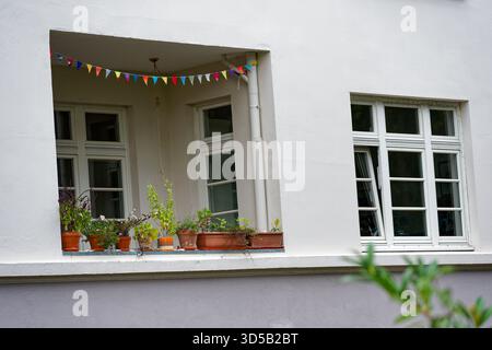 Un balcon se trouve placé à l'intérieur dans le bâtiment au lieu de faire saillie et de petits jardinières pleines de fleurs reposent le long du rail, la niche semble une personne confortable Banque D'Images