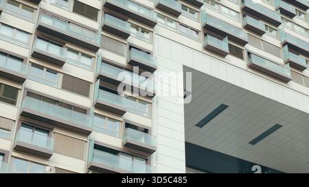 Un bâtiment urbain saisissant présente un design moderne avec de nombreux balcons dans un environnement urbain animé. Banque D'Images