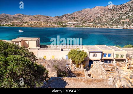 Rue étroite traditionnelle sur l'île de Spinalonga avec de vieux bâtiments en pierre et en bois sous un ciel méditerranéen bleu clair. Banque D'Images