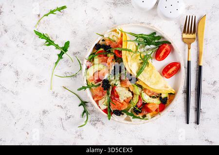 Petit déjeuner sain. Quesadilla avec omelette, saumon, avocat, caviar noir et tomates. Keto, déjeuner cétogène. Vue de dessus Banque D'Images
