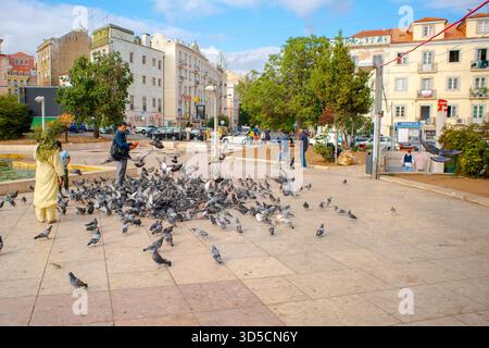 Populations asiatiques nourrissant les pigeons sur la place Martim Moniz - Lisbonne - Portugal. Banque D'Images