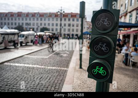 Un cycliste Glovo passant par un feu vert sur la piste cyclable, Lisbonne- Portugal. Banque D'Images