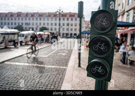 Un cycliste Glovo passant par un feu vert sur la piste cyclable, Lisbonne- Portugal. Banque D'Images