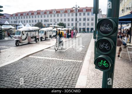Un cycliste Glovo passant par un feu vert sur la piste cyclable, Lisbonne- Portugal. Banque D'Images