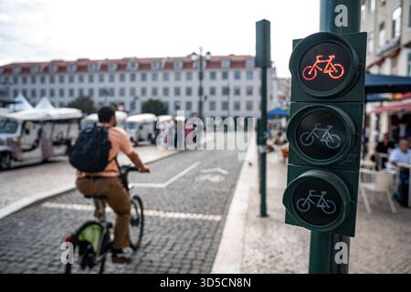 Un cycliste Glovo passant par un feu vert sur la piste cyclable, Lisbonne, Portugal. Banque D'Images