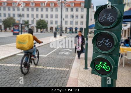 Un cycliste Glovo passant par un feu vert sur la piste cyclable, Lisbonne, Portugal. Banque D'Images