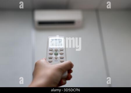 Main tenant la télécommande du climatiseur réglée à 25 degrés Celsius en mode AUTO Banque D'Images