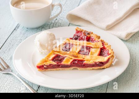 La tarte chaude et la crème glacée fraîche se marient parfaitement avec le café à la vapeur dans une lumière douce Banque D'Images