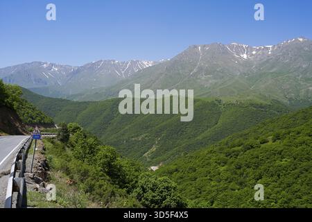 Une route de montagne sinueuse serpente à travers des collines verdoyantes avec des montagnes en arrière-plan, paysage sur M2 près du col de Meghri, col de Tashtun, province de Syunik, Banque D'Images