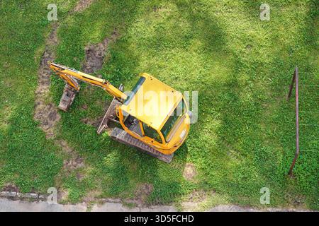 Petite pelle excavatrice, garée sur herbe verte, vue aérienne d'en haut Banque D'Images