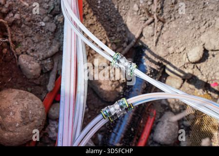 Câbles à fibres optiques industriels installés dans le sol, joints en plastique blanc visibles Banque D'Images