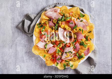 Gros plan des nachos de charcuterie avec frites, salami, fromage et olives sur une plaque vue de dessus Banque D'Images