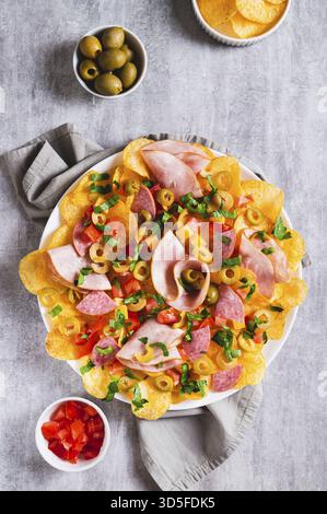 Tendance snack nachos charcuterie avec chips sur assiette sur table et vue verticale Banque D'Images