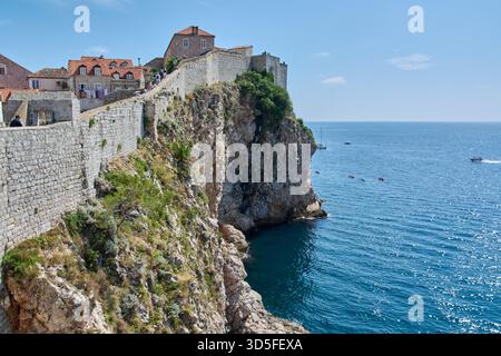 Dubrovnik. Croatie - 15 novembre 2025 : falaises époustouflantes et remparts médiévaux de Dubrovnik. Les touristes marchent sur les murs et les kayakistes pagayent en th Banque D'Images
