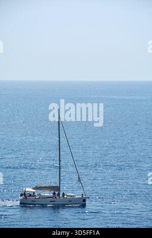 Dubrovnik. Croatie - 15 novembre 2025 : un voilier blanc avec des personnes à bord navigue sur la mer Adriatique. Le soleil scintille sur l'eau bleu profond, creati Banque D'Images