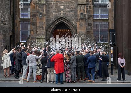 Les invités de mariage douchent la mariée et le marié avec des confettis à l'extérieur de l'hôtel Virgin à Cowgate, Édimbourg, Écosse, Royaume-Uni. Banque D'Images