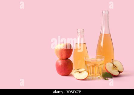 Composition avec bouteilles et verre de cidre de pomme frais sur fond rose Banque D'Images