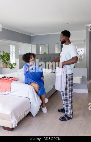 Couple choisissant des tenues ensemble dans la chambre, profitant de la routine matinale détendue Banque D'Images