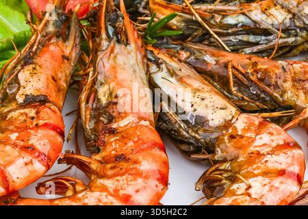 Un gros plan de plusieurs grosses crevettes géantes grillées, montrant leur couleur orange éclatante et les marques de charbon distinctes du gril. Banque D'Images