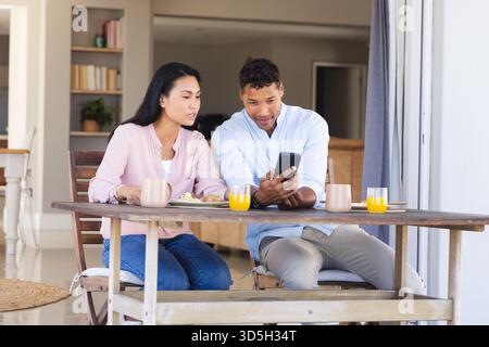 Couple appréciant le petit déjeuner sur le patio tout en regardant smartphone ensemble Banque D'Images