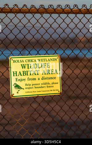 Un panneau indiquant la zone d'habitat faunique est affiché sur une clôture à maillons de chaîne dans les zones humides de Bolsa Chica à Huntington Beach, en Californie. Crédit : Erik Morgan Banque D'Images